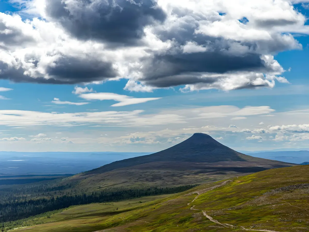 Fjäll med en spetsig bergstopp under molnig himmel i Dalarna och Härjedalen.